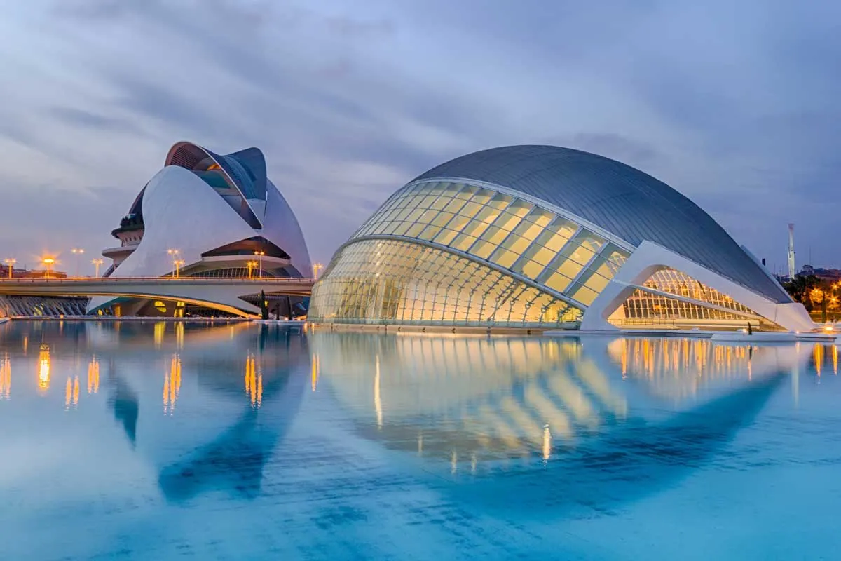 L'Oceanogràfic lit up at night with reflections in the surrounding waters.