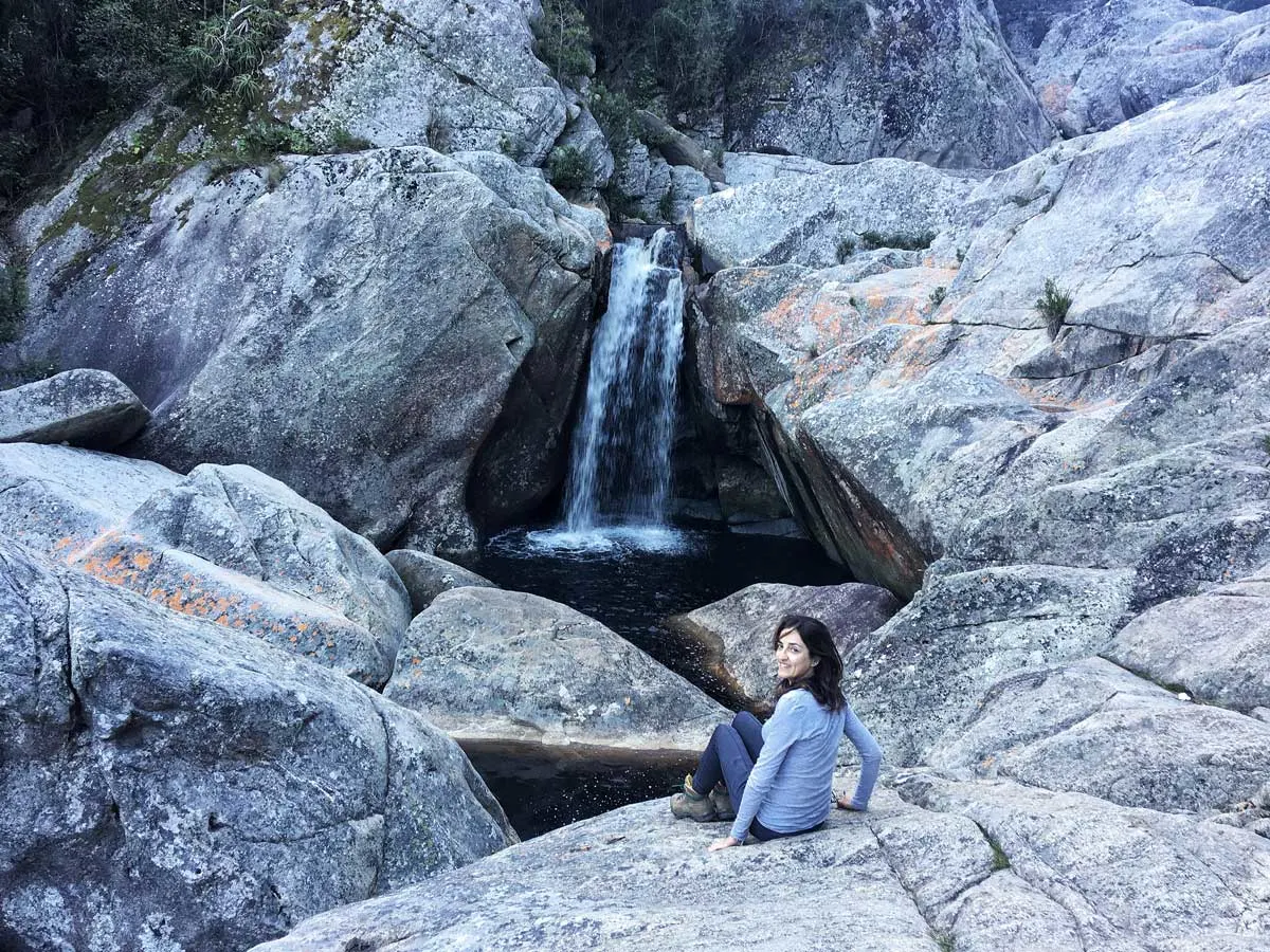 Hiker resting on the rocks by a pool and small waterfall along the Garden Route, South Afica.