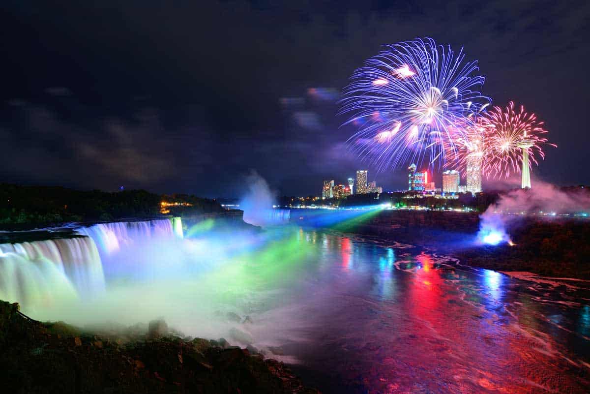 Winter fireworks are the backdrop to the illuminated Niagara Falls in winter.