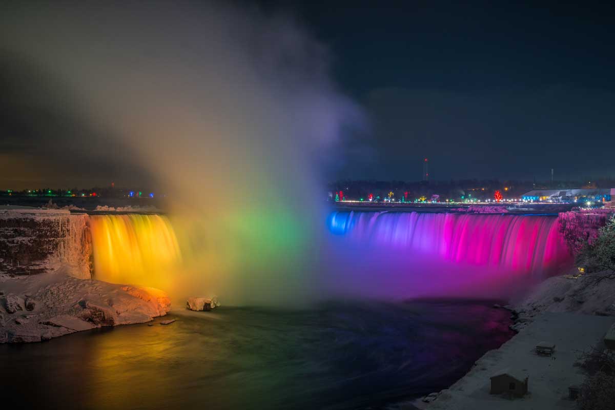 Niagara Falls at night with the rainbow lights on the water.