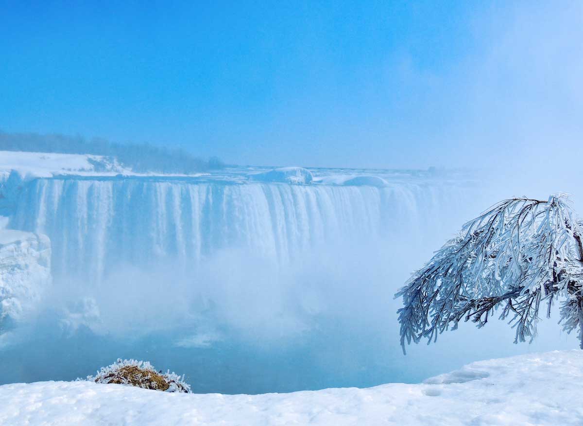 Blue skies and white snow frame the icy mist around Niagara Falls.