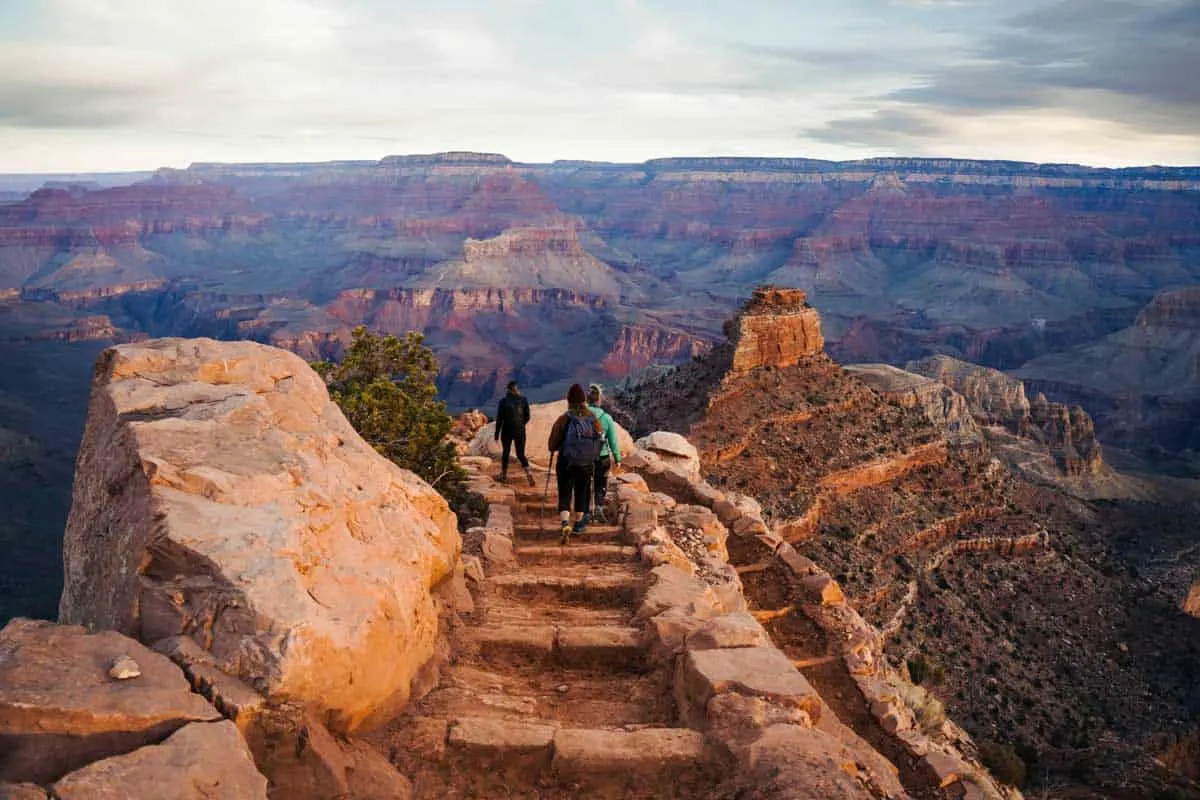 A group of hikers heading along the stone step path leading down into the Grand Canyon.