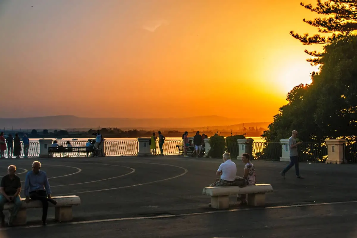 People enjoying the orange glow of sunset at Ortigia Syracuse.