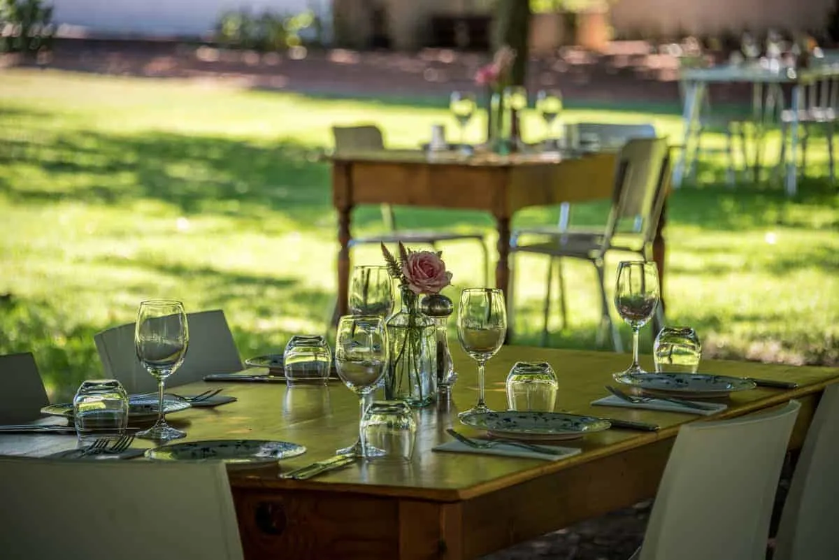 Table set with wine glasses and roses in the garden of a Cape Town Vineyard. 
