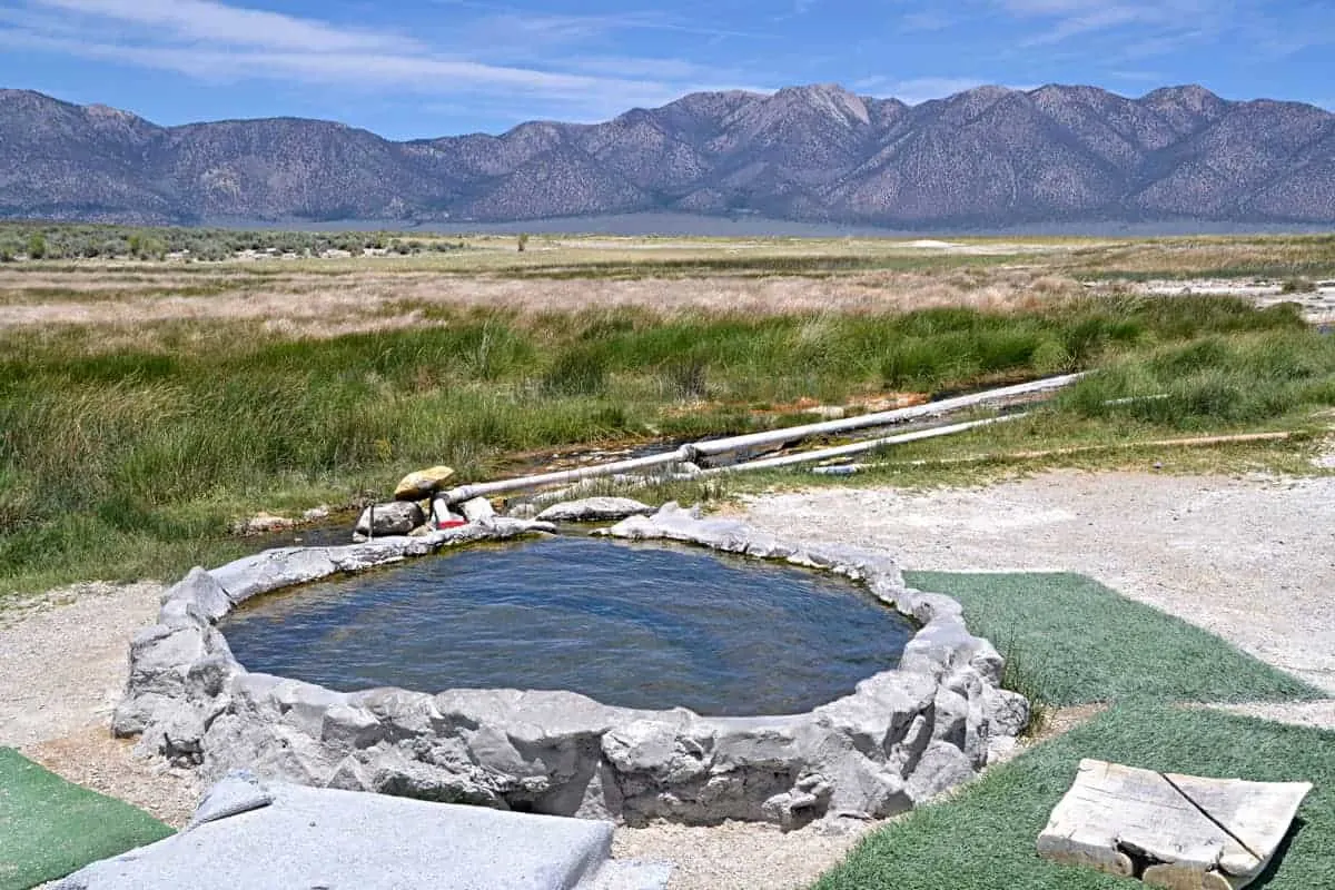 Small rock hot tub pool with mountain views in the distance. 