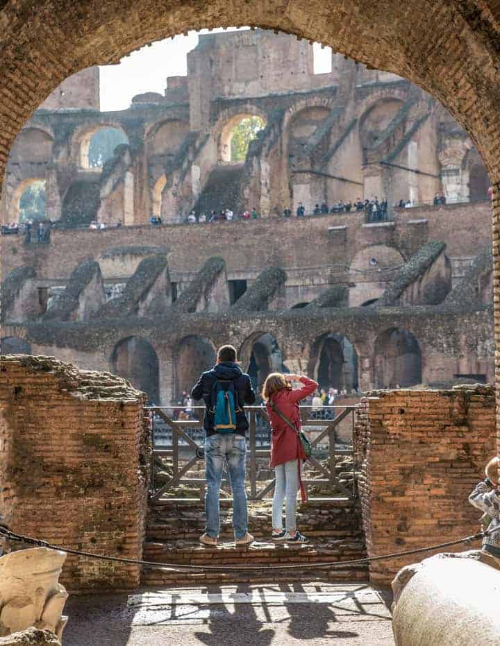 Young man and girl from behind taking photos in the Colosseum in Rome. 