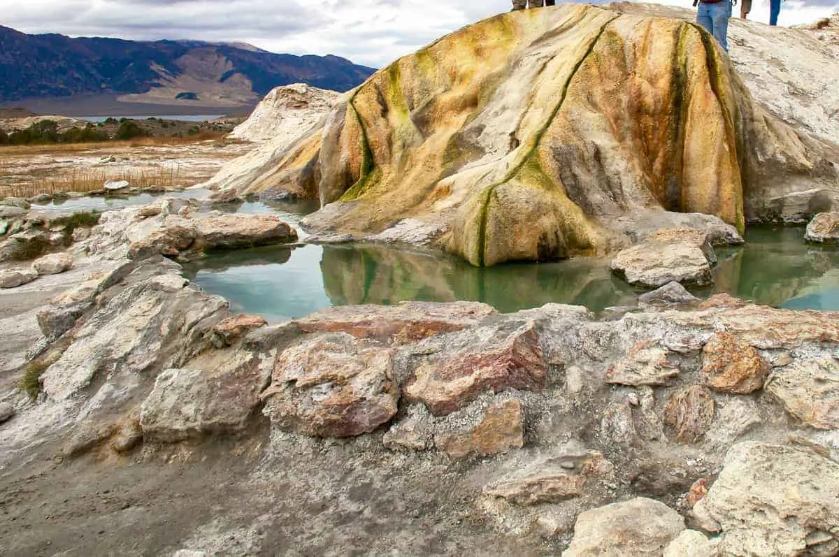 Hot spring pools surrounded by rocks with mountain views in the background. 