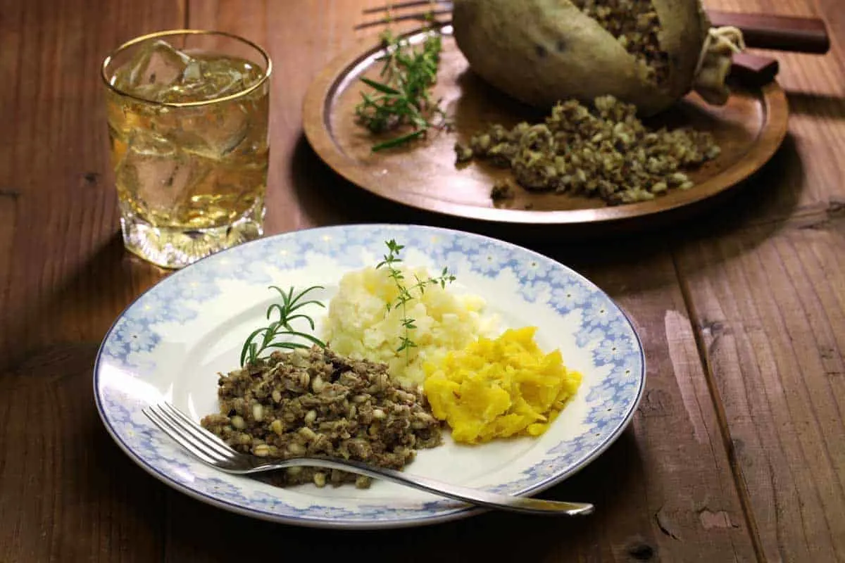 Plate of traditional haggis neaps and tatties with a glass of whiskey. 
