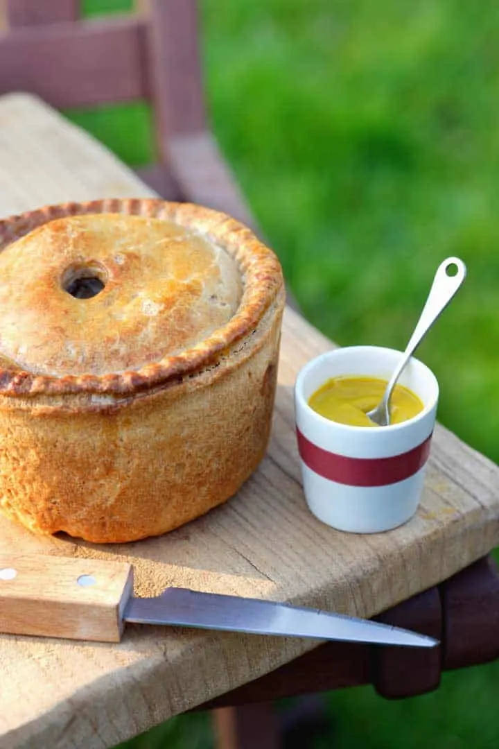 Pork pie with a small bowl of mustard.