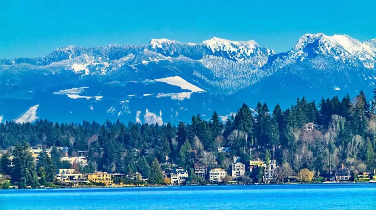 Bellevue Washington with the lake in the forground and snow capped mountains behind.