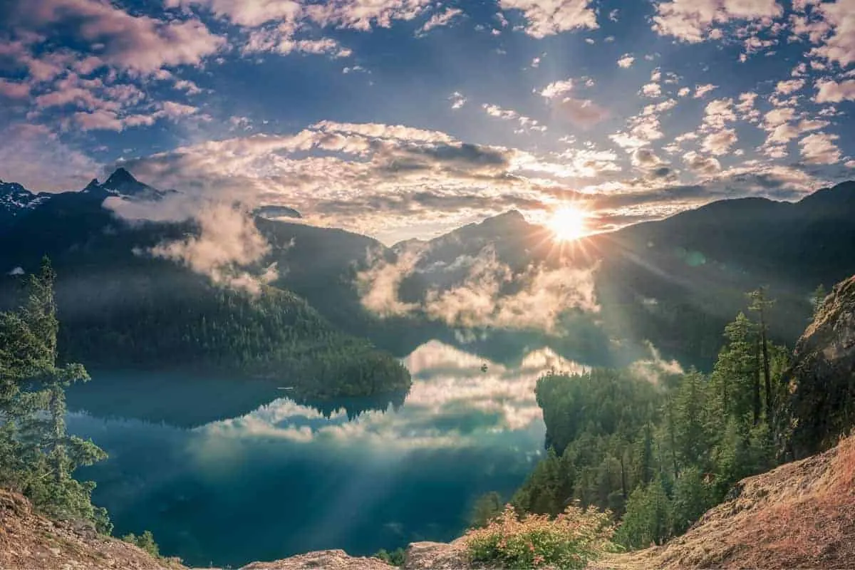Shining sunset and fog patches over lake and mountains at North Cascade National Park