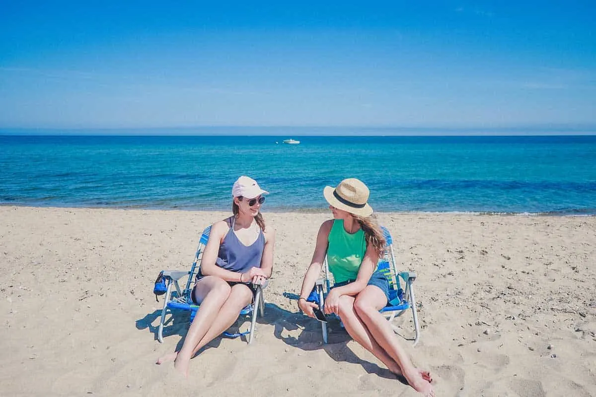 Two young women sitting on beach chairs on the beach in Cape Cod in front of the sea. 