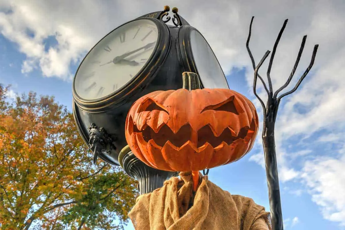 Jackolantern next to an old fashioned street clock.