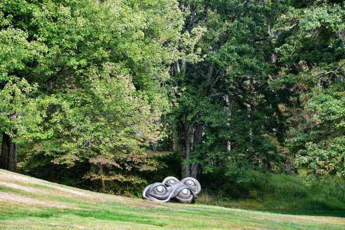 Large abstract sculpture of eyes in a garden setting.