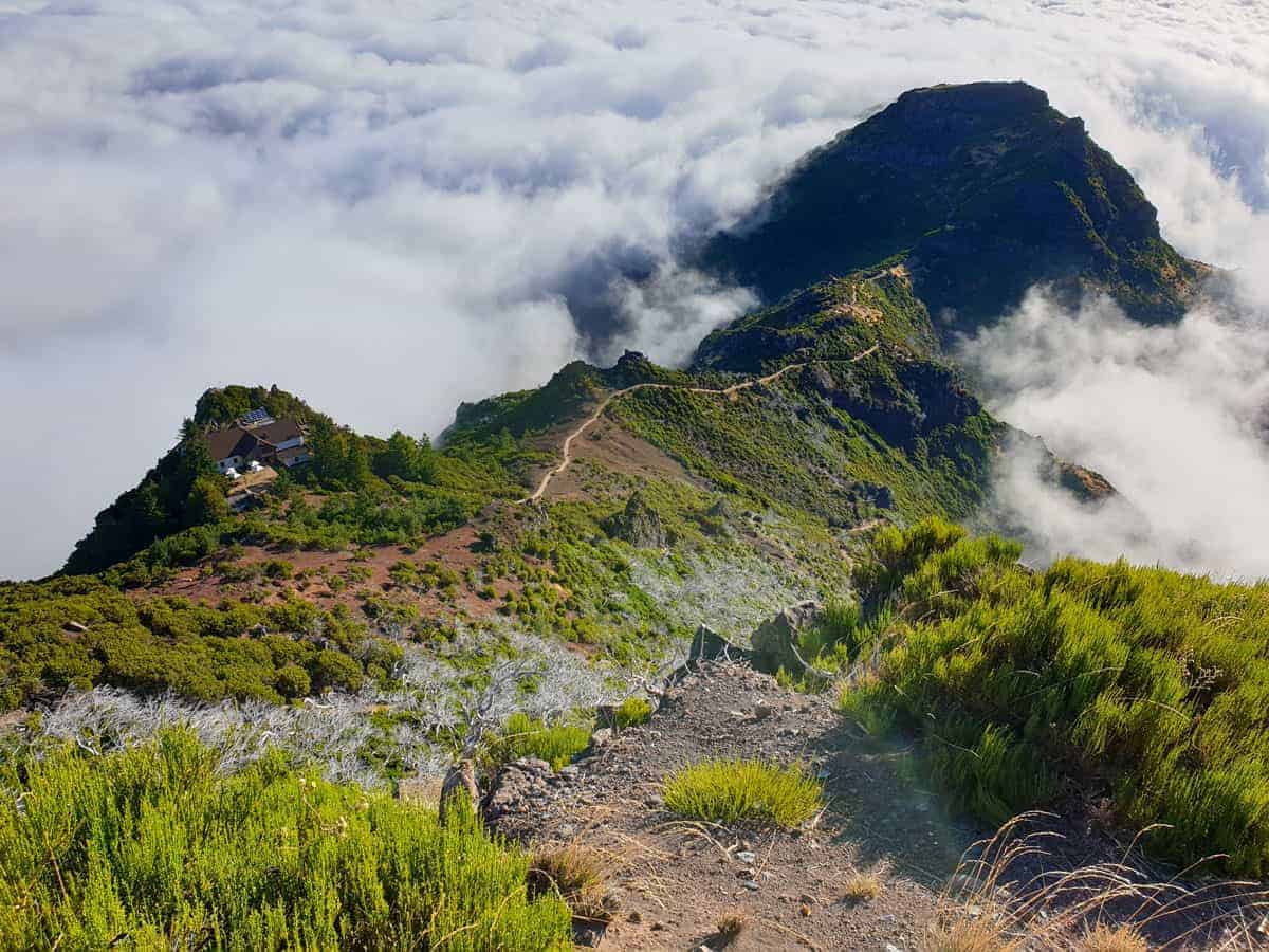 Hiking trail and house on a mountain peak above the clouds in Madeira Portugal.