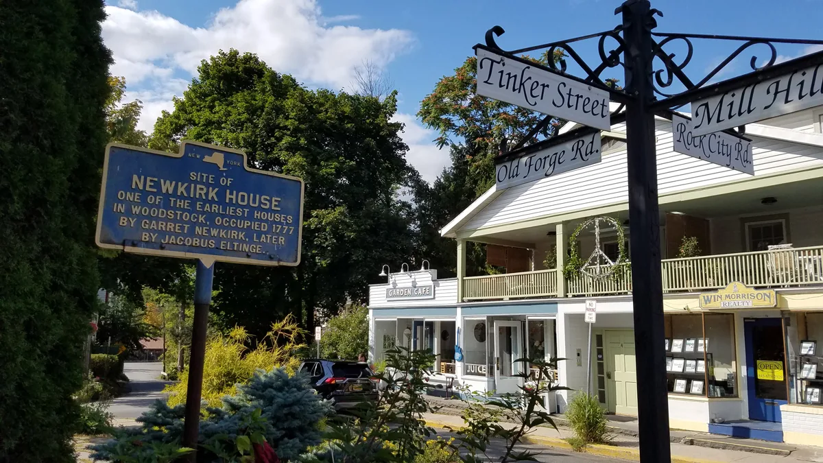 Street signs in Woodstock showing the crossroads of streets with original wooden houses in the background. 