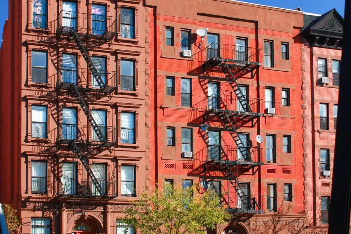 Iconic brick apartment buildings in Harlem with external fire escape stairs. 