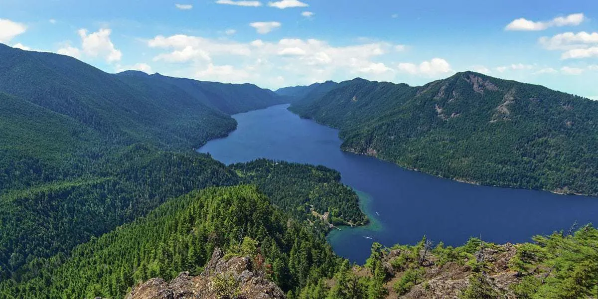 Sumit views over blue lake in Olympic National Park.