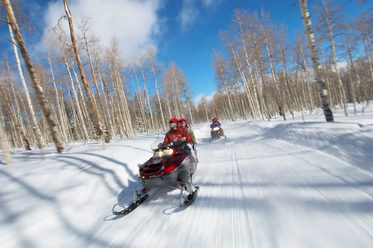 A couple travelling fast on a snowmobile.