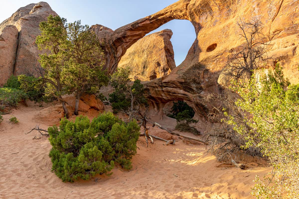 Arch and hole in the canyon wall on a hiking trail in Moab Utah.