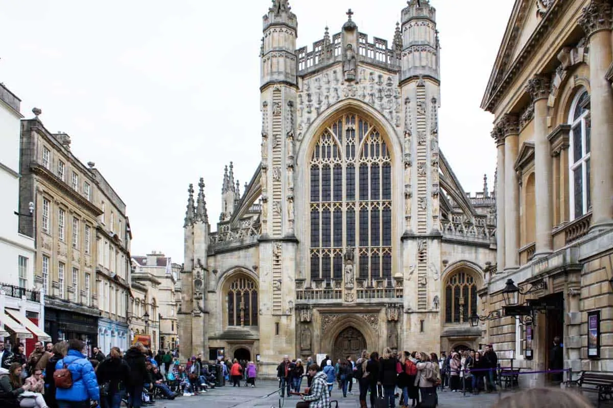 Exterior of Bath Abbey with pedestrians and buskers in front.