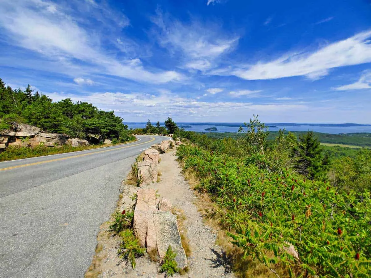 Road with ocean view in the distance on the park Loop Drive in Maine.