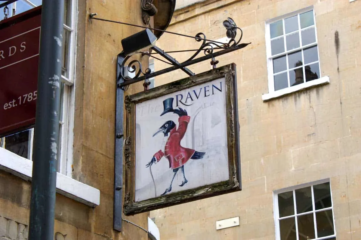 Sign for the Raven Pub with a Raven wearing a top hat. 