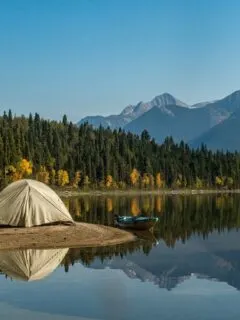 small tent on the banks of a lake reflected in the water.
