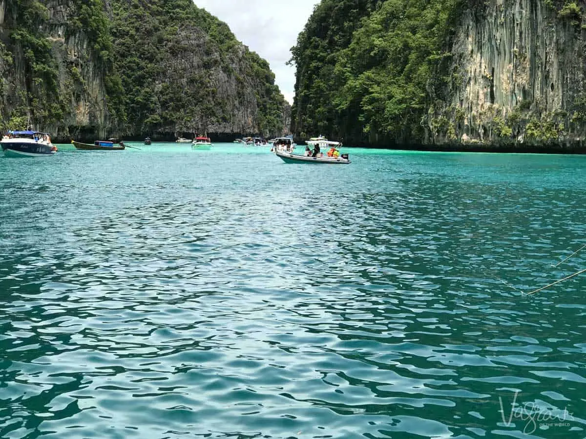 Boats moored in a bay surrounded by cliffs in Thailand. 