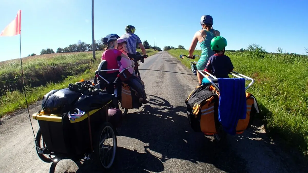 Family cycling towing camping gear.