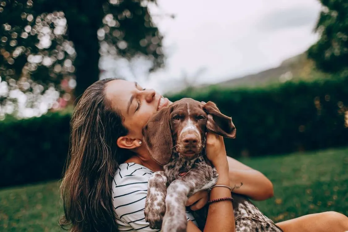 Woman in nature hugging her dog.