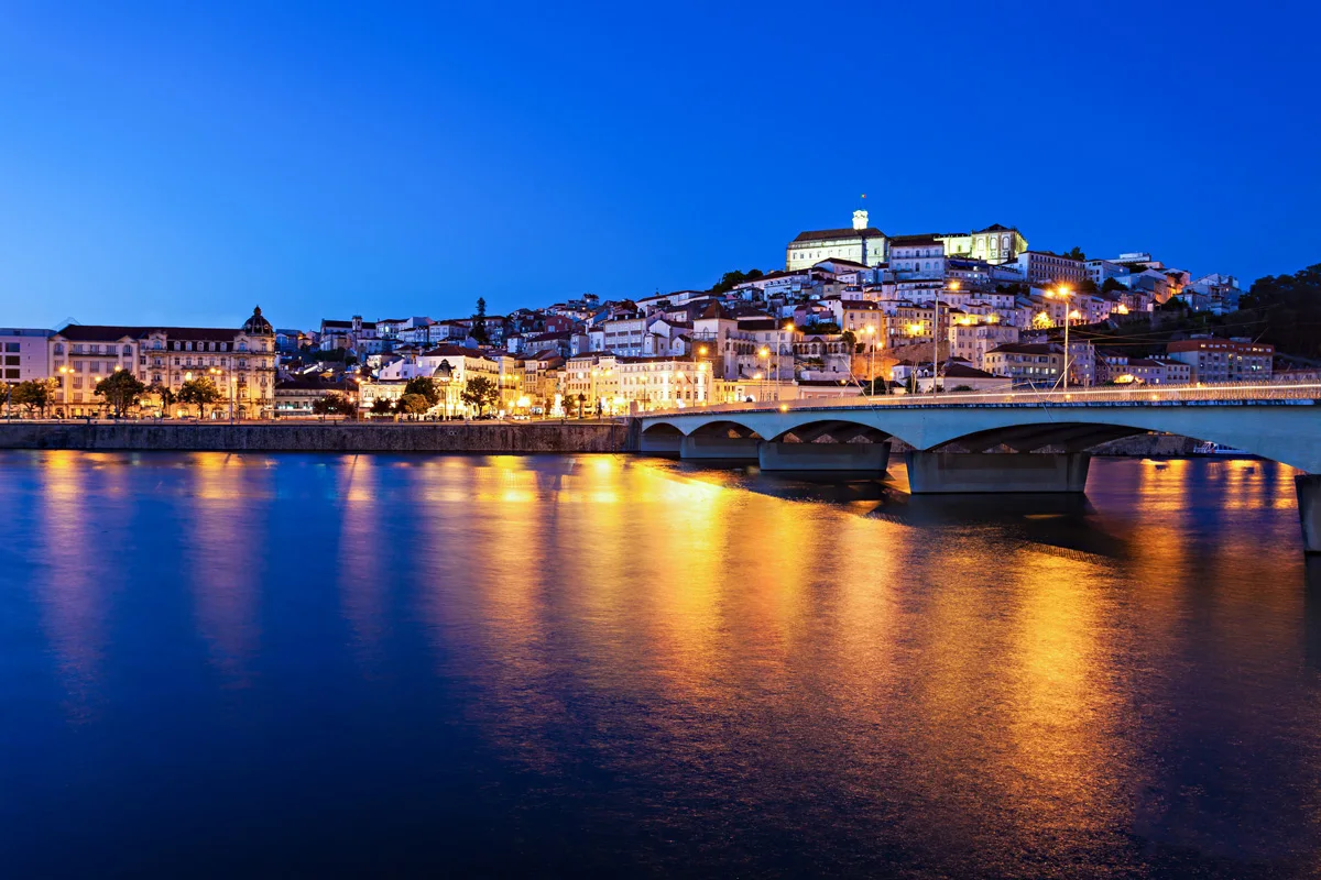 Coimbra city Portugal at night reflecting on the river.