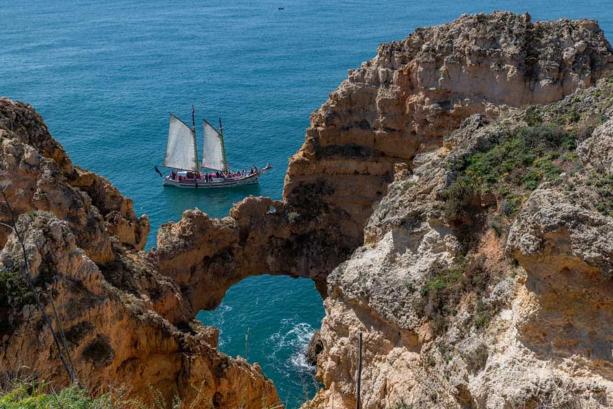 The cliffs of Lagos with a sailing oat cruising past under full sail. 