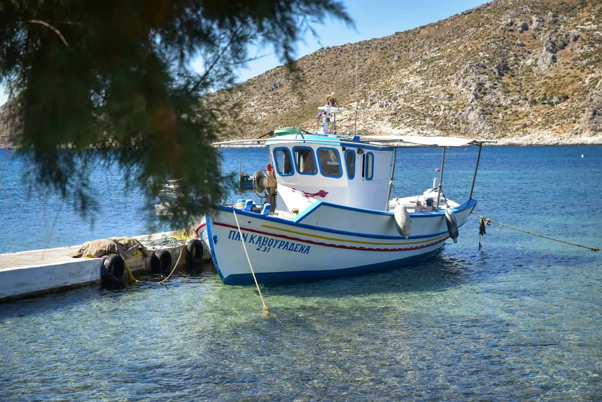 Typical Greek fishing boat tied up on crystal clear water on Leros Island
