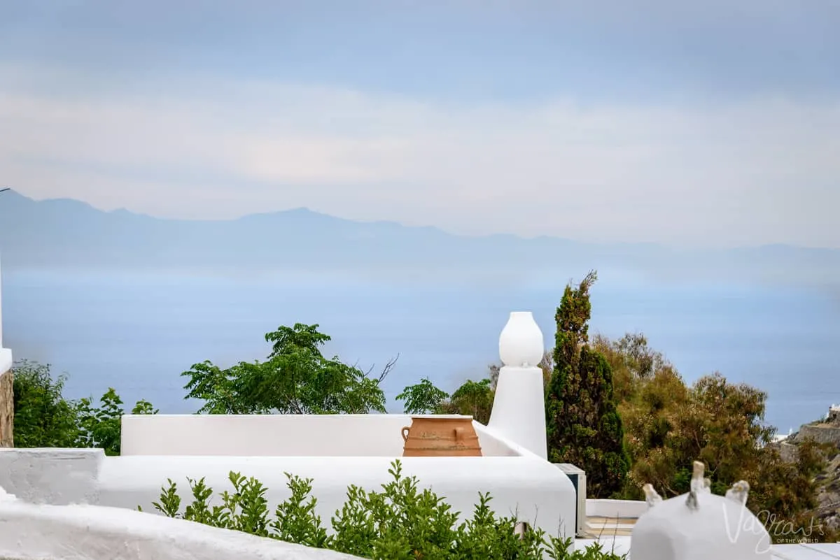 White painted terrace with terracotta pot overlooking the ocean in Mykonos.