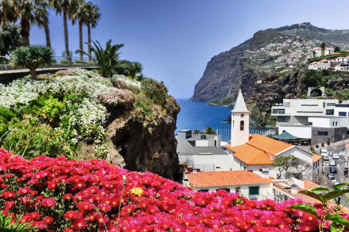 Bright flowers and a church spire overlooking the ocean in Madeira Island.
