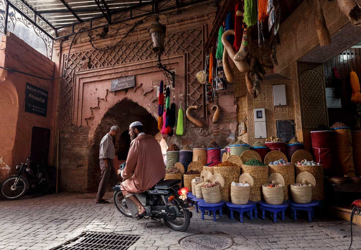 Islamic man riding a motorcycle through the Marrakech Medina.
