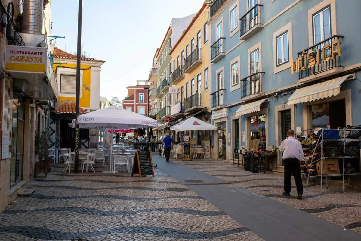 The main street of Cacilhas in Lisbon with mosaic sidewalk and fish restaurants. 