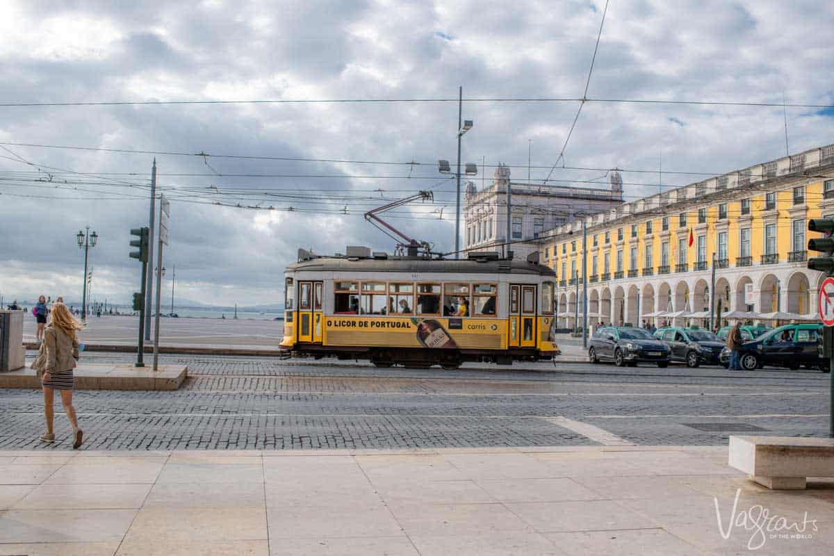 A girl crossing the street in front of an iconic yellow tram in Lisbon.