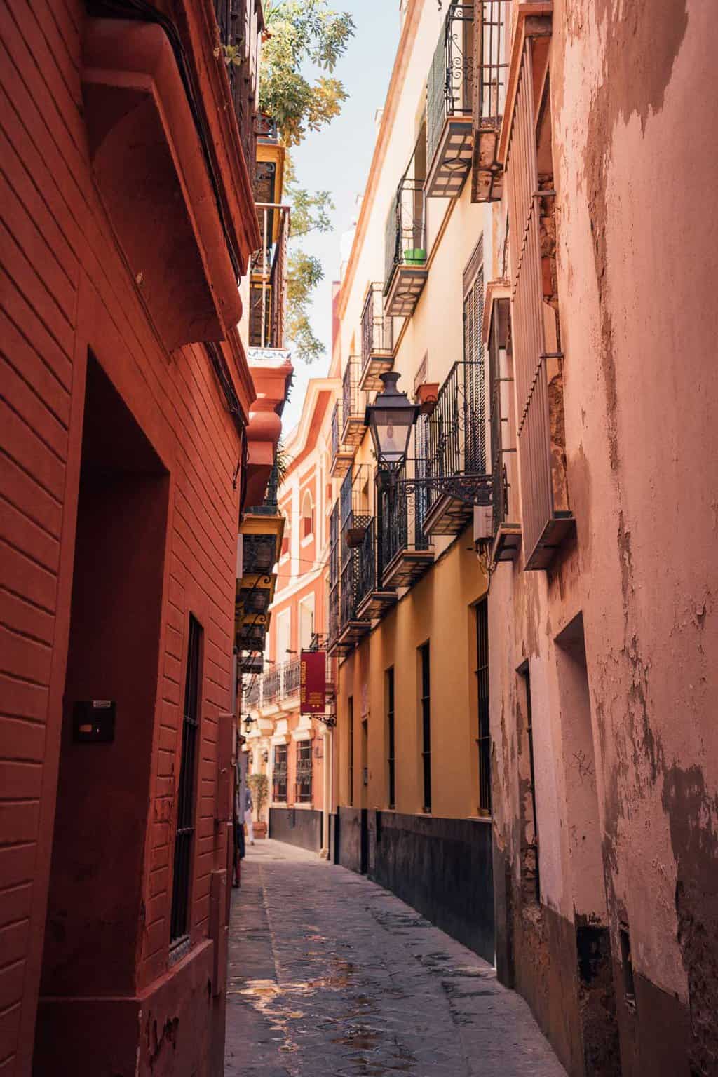 The atmospheric narrow red and yellow streets of Barrios Santa Cruz in Seville.
