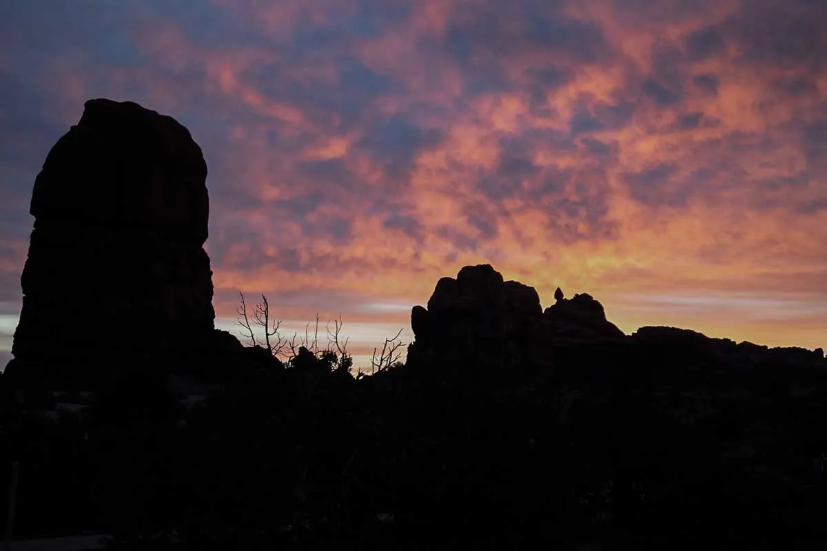 Sunrise with silhouetted rocks in Arches National Park.