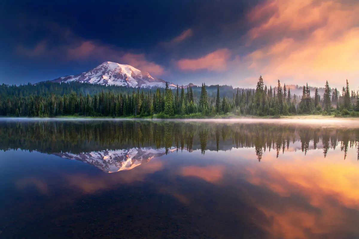Snow capped mountain reflected in a lake at sunset in Mount Rainier National park. 