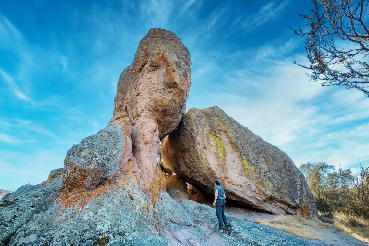 man standing in front of unique rock formation in Pinnacles national park. 