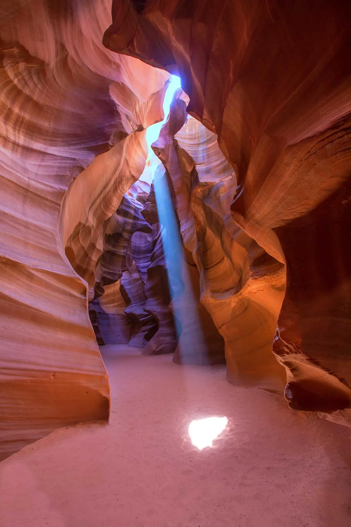 Light coming through a slot in the red canyon onto the red sand in Antelope Canyon. 