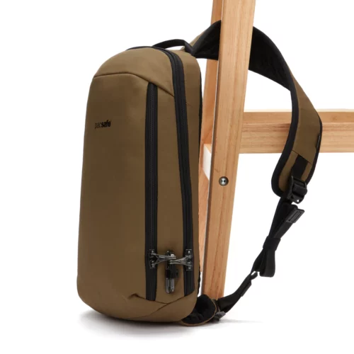 Tan and black Pacsafe Anti theft Sling backpack attached to a chair leg. 