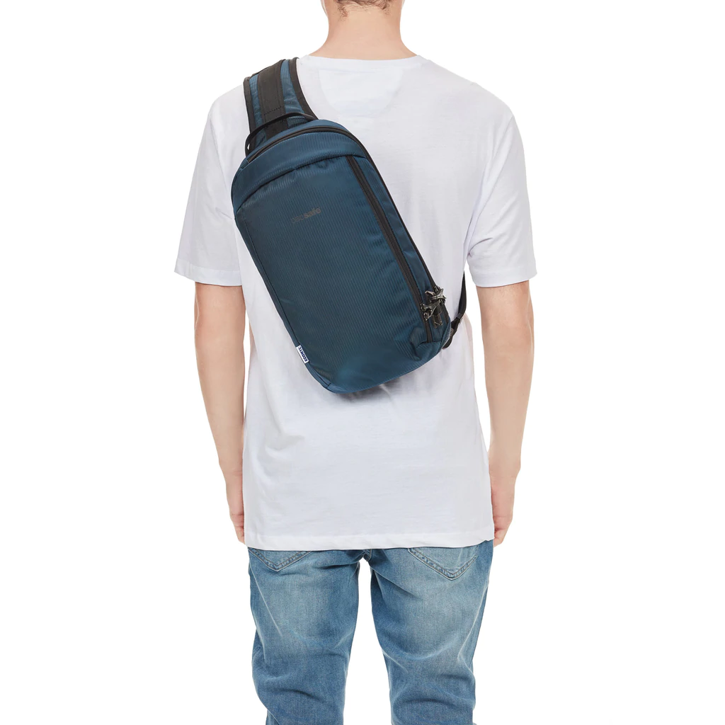 Man in white T shirt wearing a blue sling backpack. 