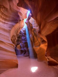 Light coming through a slot in the red canyon onto the red sand in Antelope Canyon.