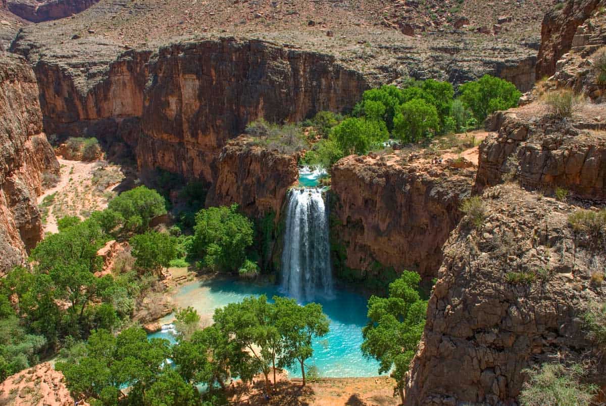 Brilliant blue water against red rocks at the Havasu Falls Oasis in the middle of the Arizona.