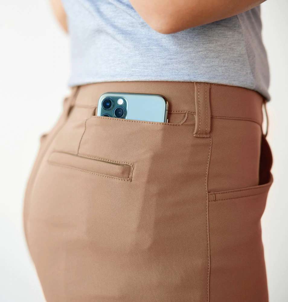 Lady modelling the rear phone pocket in a pair of tan travel pants.