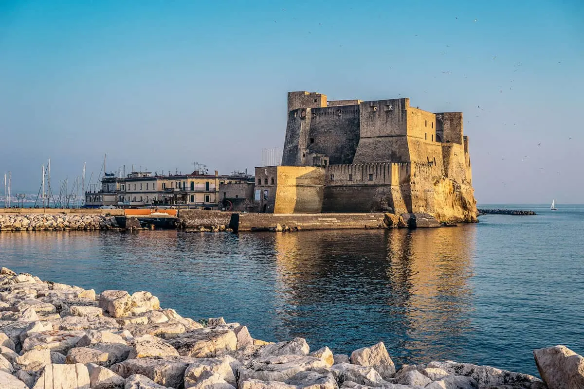 Castel Del Ovo reflected in the rippled water of the Naples harbour at sunset. 